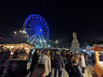People in amusement park against sky at night