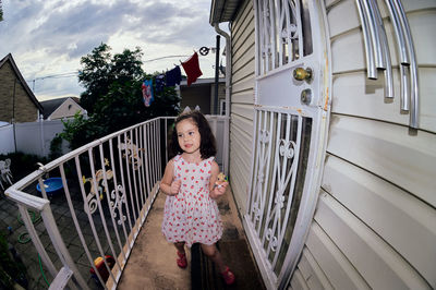 Cute young girl in a summer dress playing in a suburban backyarrd