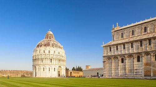 Pisa cathedral and baptistery against clear blue sky