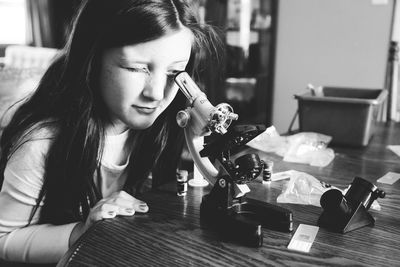 Girl using microscope at table in school