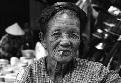 Close-up of portrait of senior woman with cigarette sitting outdoors