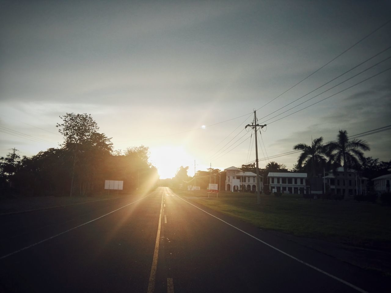 sunset, sun, transportation, sky, cable, road, no people, silhouette, built structure, tree, the way forward, outdoors, electricity pylon, building exterior, architecture, nature, day