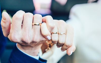 Cropped image of bride and groom with rings connecting fingers during wedding