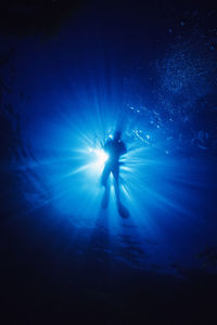 A silhouette of a scuba diver with a camera