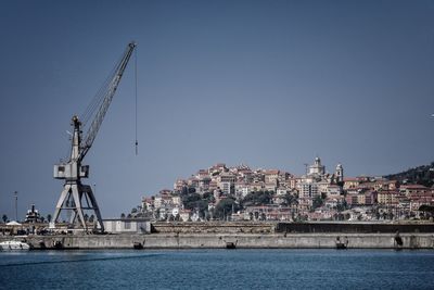 Cranes by buildings against sky