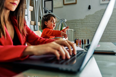 Young executive woman working from home while taking care of her young daughter