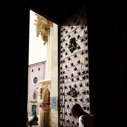 Rear view of woman leaning against window of building