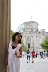 Young woman standing against building