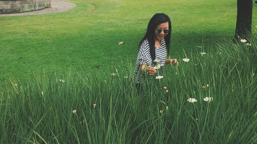 Mid adult woman picking flowers on grassy field