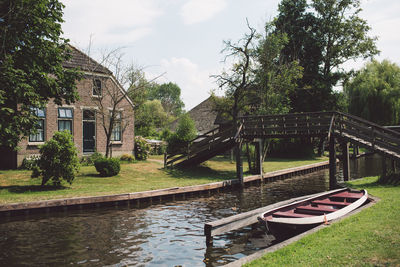 Canal amidst trees and buildings against sky