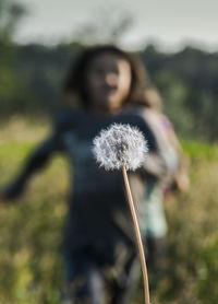 Close-up of dandelion flower on field against sky