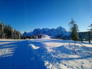 Scenic view of snow covered mountains against clear blue sky