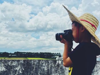 Rear view of woman photographing against sky