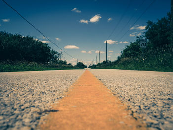 Road by trees against sky