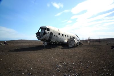 Abandoned airplane on airport runway against sky