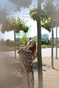 Portrait of woman standing by tree