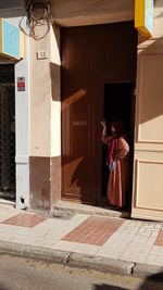 Rear view of woman standing at entrance of building