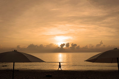 Silhouette man standing on beach against sky during sunset