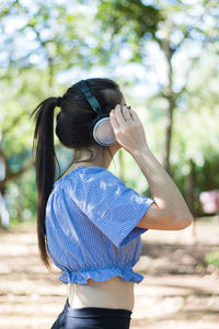 Rear view of woman with umbrella standing against trees