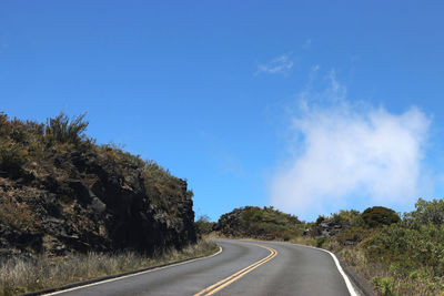 Road amidst trees against blue sky