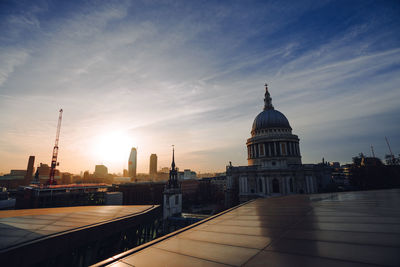 Solar panels against buildings in city during sunset