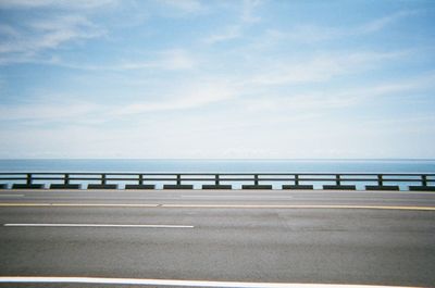 Empty road by sea against sky