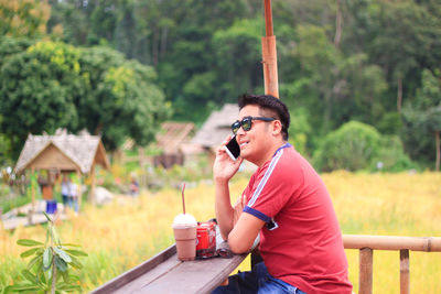 Side view of man talking on phone while sitting outdoors