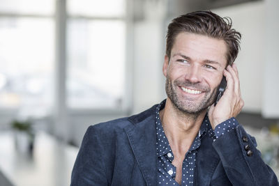 Happy businessman using mobile phone in office