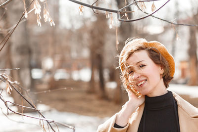 Portrait of a smiling young woman standing outdoors in early spring time