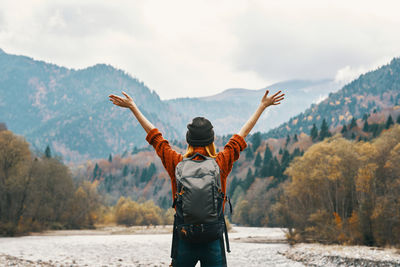 Rear view of man standing on mountain against sky