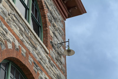 An old street lamp, on the corner of the facade of a house, on a street