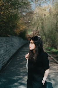 Young woman standing against trees