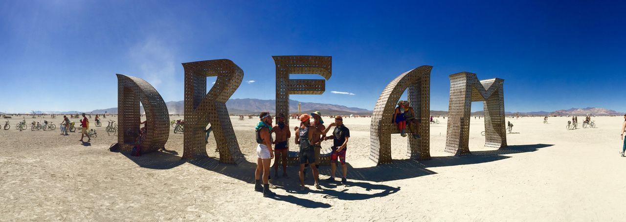 blue, beach, large group of people, sand, leisure activity, men, sunlight, lifestyles, clear sky, sky, day, shadow, person, vacations, tourism, outdoors, panoramic, built structure, sunny