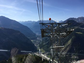 Overhead cable car over mountains against sky