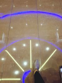 Low section of woman standing by illuminated lights