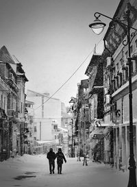 Rear view of two people walking down the street