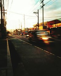 Cars on road in city against sky at sunset