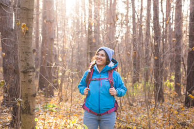 Smiling young woman standing in forest during winter