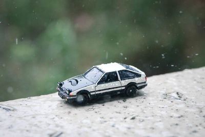 Close-up of toy car on retaining wall during rainy season