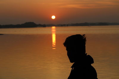 Silhouette man standing at beach during sunset