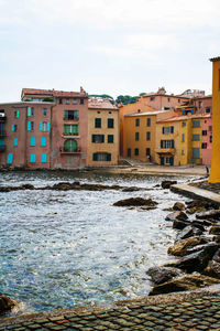 Buildings by river against sky in city