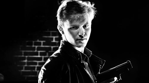 Portrait of confident man with handgun in darkroom