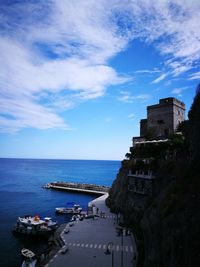 Buildings by sea against blue sky