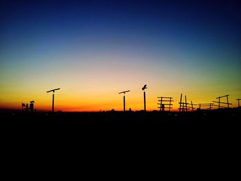 Silhouette windmills against clear sky during sunset