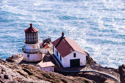 High angle view of lighthouse on cliff by sea