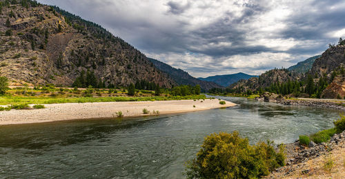 Scenic view of river by mountains against sky