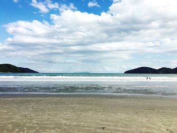 Scenic view of beach against cloudy sky