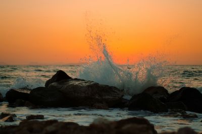 Waves splashing on rocks at sunset