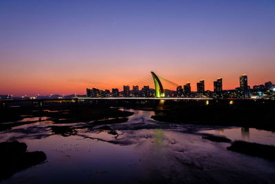 Reflection of illuminated city at sunset