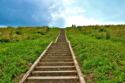 Boardwalk amidst field against sky